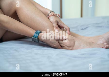 Mani femminili che tengono i vitelli delle gambe. Dolore alle gambe. Spremere e massaggiare per rilassarsi. Foto Stock