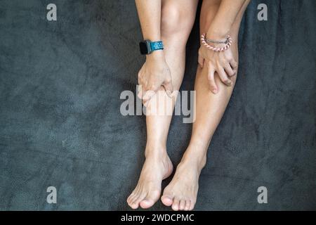 Mano di donna che tiene la coscia, dolore alle gambe spremere e massaggio per rilassarsi. Foto Stock
