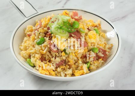 Riso fritto giapponese Yakimeshi con uovo, peperoni di manzo ed Edamame. Chiudere Uo su piastra bianca. Foto Stock