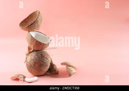 Vecchio Copra di frutta di cocco biologico marrone spezzato a pezzi e impilato su sfondo rosa. Copia spazio per testo Foto Stock