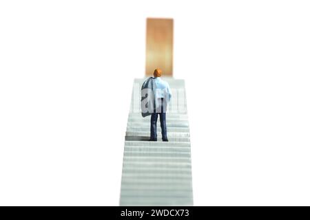 Fotografia di figure giocattolo in miniatura. Illustrazione del concetto di business. Un uomo d'affari che sale su una scala a porta. Isolato su uno sfondo bianco Foto Stock