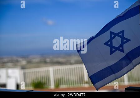 Un'unica bandiera israeliana isolata in primo piano e sullo sfondo offuscata è la vista di un insediamento israeliano Foto Stock