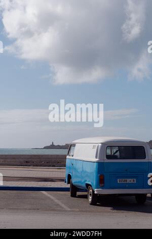 Camper blu e bianco parcheggiato con il mare e l'isola alle spalle, a Essaouira, Marocco, 19 gennaio 2024 Foto Stock