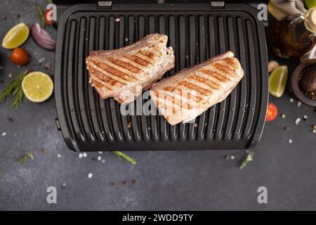 Due pezzi grigliati di filetto di tonno su una griglia elettrica nella cucina domestica Foto Stock