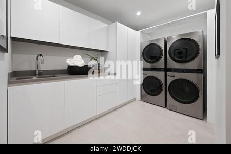 Una lavanderia con eleganti armadi bianchi, una moderna stufa nera e una lavatrice all'avanguardia, New Construction Home a Tarzana, California Foto Stock