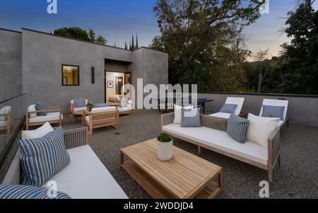 Mobili e tavoli da esterno disposti in un tranquillo cortile sul retro durante le ore diurne, nuova casa di costruzione a Tarzana, California Foto Stock