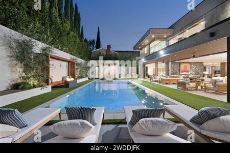 Una piscina coperta circondata da una vegetazione lussureggiante, adornata da comode sedie e un tavolo, nuova casa di costruzione a Tarzana, California Foto Stock