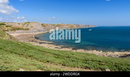 Un'ampia baia, sulla costa del Galles meridionale, vista dal sentiero costiero del Galles. La giornata è soleggiata e l'acqua è blu. Foto Stock