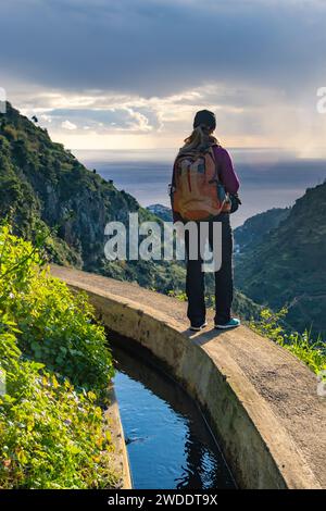 Turista a Levada do Norte sull'isola portoghese di Madeira. Canale di irrigazione di Levada. Escursioni a Madeira. Sentiero stretto vicino alla levada. Verde Foto Stock