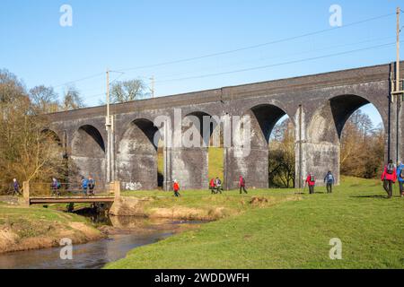 Gruppo di escursionisti a piedi nella campagna del Cheshire camminando lungo il fiume Dean avvicinandosi al viadotto ferroviario vicino a Wilmslow Cheshire Foto Stock