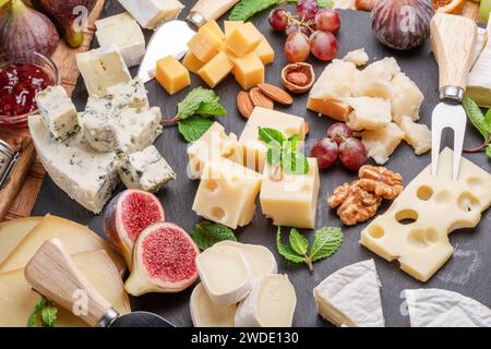 Varietà di formaggi a fette con frutta, menta, noci e taglierini. Un meraviglioso sfondo di formaggi per i vostri progetti. Foto Stock