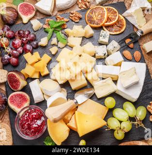 Varietà di formaggi a fette con frutta, menta, noci e taglierini. Un meraviglioso sfondo di formaggi per i vostri progetti. Foto Stock
