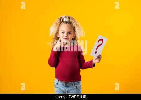 Esplorazione incantevole. Un ritratto di una bambina premurosa che regge carte con punti interrogativi e punti esclamativi, evocando l'essenza di Childr Foto Stock