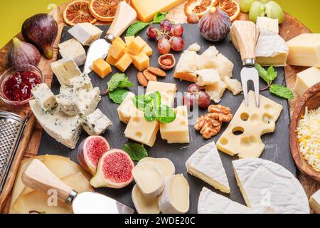 Varietà di formaggi a fette con frutta, menta, noci e taglierini. Un meraviglioso sfondo di formaggi per i vostri progetti. Foto Stock