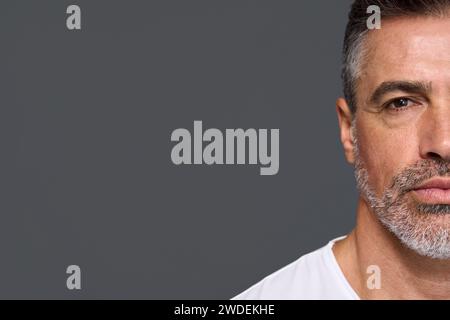 Un uomo anziano serio isolato su sfondo grigio. Primo piano in verticale. Foto Stock