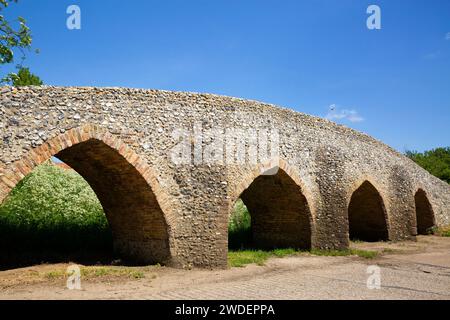 Lo storico Packhorse Bridge del XV secolo con i suoi quattro archi sul fiume Kennett nel villaggio di Moulton, Suffolk Foto Stock