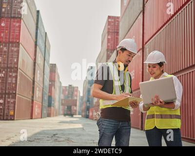 Giovane donna asiatica e ingegnere che lavora con un collega presso un cantiere di container all'estero. Foto Stock