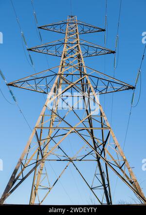 Guarda verso l'alto il pilone elettrico della rete nazionale da un angolo basso, da sotto, Inghilterra, Regno Unito, con cielo azzurro Foto Stock
