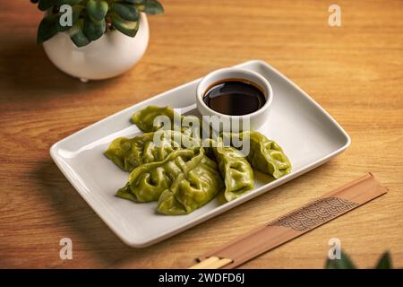 Vassoio di gnocchi ripieno di spinaci cinesi al vapore serviti con salsa di soia Foto Stock