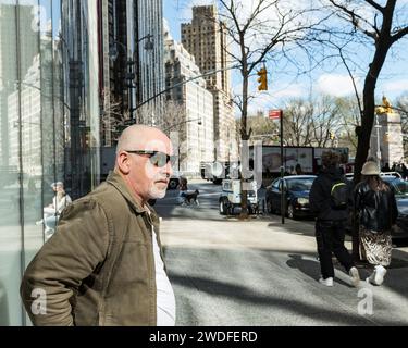 Uomo in piedi all'angolo tra W 58th St e Broadway, guardando verso Columbus Circle e Central Park, Manhattan, New York. Foto Stock