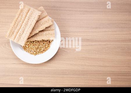 Pane croccante di grano saraceno e grano saraceno su piatto su fondo di legno, senza glutine. Biscotti dietetici Foto Stock