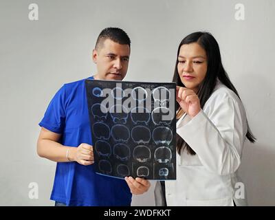 Neurologo latina medico specialista donna e infermiere maschile dalla pelle scura esaminano la radiografia del cervello del paziente per discutere di casi di studio e ricerche straordinari Foto Stock