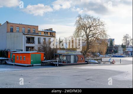 Berlino, Germania - 19 gennaio 2024: Vista sulla casa galleggiante di una società di noleggio barche sul fiume ghiacciato Dahme a Berlino Koepenick. Foto Stock