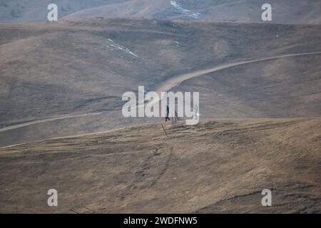 20 gennaio 2024, Srinagar Kashmir, India: I visitatori camminano lungo le piste da sci di Gulmarg, a circa 55 km da Srinagar. Il lungo periodo di tempo invernale secco nel Kashmir ha inferto un duro colpo all'iconica località sciistica di Gulmarg. Le piste da sci, un tempo trafficate, sono oggi aride, causando delusione tra gli appassionati di sci. L'assenza di nevicate sostanziali ha provocato un'ondata di cancellazioni delle prenotazioni per i proprietari di hotel, con un grave impatto sulle loro attività. Questa battuta d’arresto imprevista sottolinea la vulnerabilità delle economie dipendenti dall’inverno e l’urgente necessità di strategie per mitigare il Foto Stock