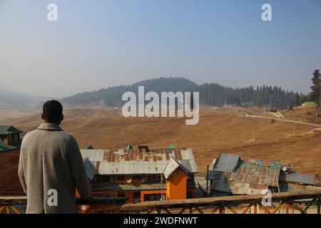 20 gennaio 2024, Srinagar Kashmir, India: Anis Khan, manager dell'Origins Twelve Hotel guarda le piste da sci di Gulmarg, a circa 55 km da Srinagar. Il prolungato periodo di secchezza di quest'inverno nella valle del Kashmir ha inferto un duro colpo alla famosa stazione sciistica di Gulmarg. Le piste da sci, un tempo trafficate, sono ormai senza neve e sono motivo di delusione per i turisti e in particolare per gli appassionati di sci. L'assenza di nevicate stagionali ha comportato la cancellazione delle prenotazioni di massa per i proprietari di hotel, con un grave impatto sulle loro attività. Questa battuta d'arresto imprevista sottolinea la vulnerabilità della dipendenza invernale Foto Stock