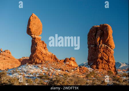 Balanced Rock in Arches National Park, montagne LaSal sullo sfondo. In inverno al tramonto. Foto Stock