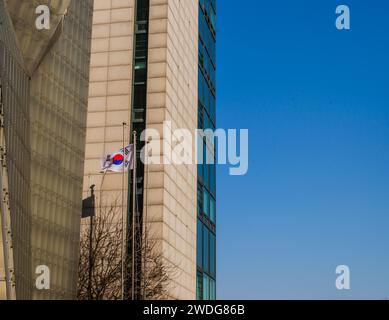 Una bandiera sudcoreana che sventola di fronte ad un edificio con un cielo azzurro a Seoul, Corea del Sud Foto Stock