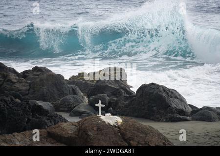 primo piano sulle onde ondulate e che si infrangono sull'isola tropicale di la Réunion, in Francia, vicino alla costa rocciosa con una croce bianca Foto Stock