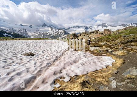 Gli alpinisti si trovano su un sentiero escursionistico nel pittoresco paesaggio montano, cime montane con neve e ghiacciaio Schwarzensteinkees, Hornkees e Waxeggkees Foto Stock