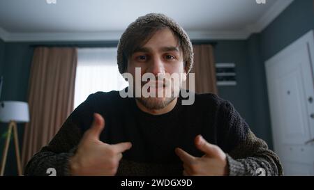 Bell'uomo con un beanie vlogger che fa videochiamate online, registra il blog vlog che parla con la fotocamera guardando la webcam a casa. Videoclip e social media Foto Stock