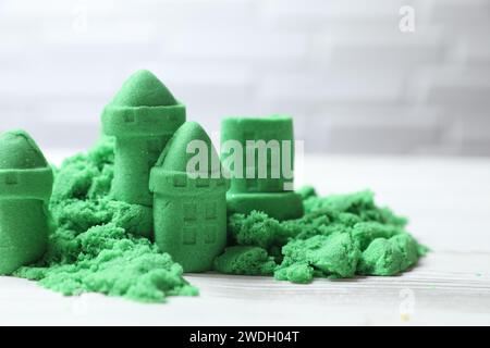 Figure del castello fatte di verde sabbia cinetica su un tavolo bianco, primo piano Foto Stock