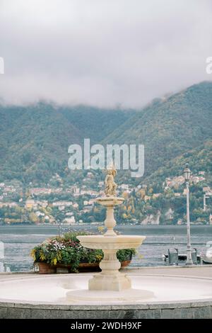 Fontana di Cernobbio con una statua vicino a un letto di fiori sulle rive del Lago di Como. Italia Foto Stock