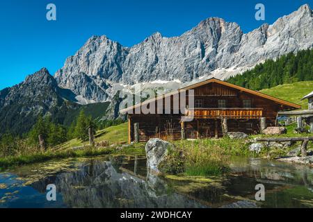 Maestoso scenario alpino, accogliente casetta in legno sulla piccola riva del lago e splendide montagne sullo sfondo, gruppo montuoso Dachstein, Ramsau am Foto Stock