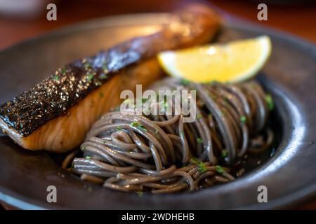 Noodle di soba fredda con salmone scottato in padella servito su piatto con limone Foto Stock