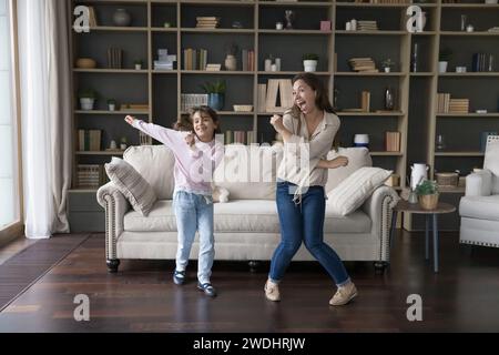 Vivace bambina che balla in salotto con una madre attiva Foto Stock