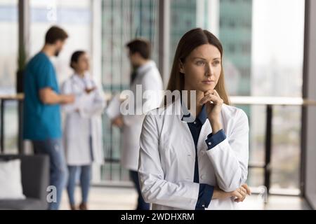 Grave medico capo donna in piedi nello spazio della sala dell'ospedale Foto Stock