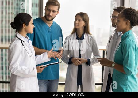 Serio giovane medico indiano che parla con personale medico diverso Foto Stock