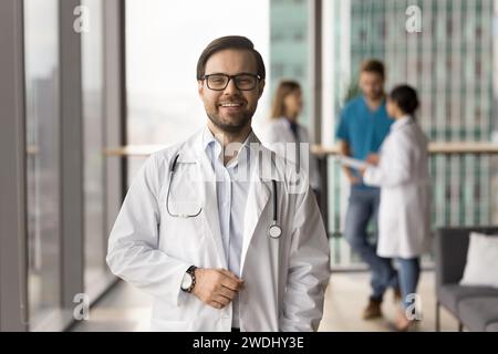 Felice uomo medico di successo in posa con la riunione del team alle spalle Foto Stock