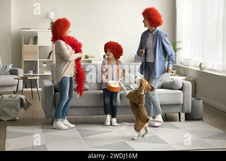 Ragazza attiva, mamma, nonna con parrucche rosse che ballano con il cane Foto Stock