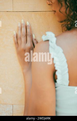 Vista posteriore di una donna appoggiata al muro all'esterno Foto Stock