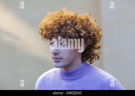 ritratto di un giovane uomo caucasico dai capelli rossi ricci con scollo v polo all'aperto invernale su pareti in tinta beige con sfondo solido Foto Stock