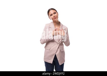 giovane donna bruna elegante vestita con giacca beige e jeans su sfondo bianco Foto Stock