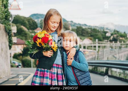 Ritratto all'aperto di un grazioso bambino con un bel bouquet di fiori autunnali. Moda scolastica per bambini, abbigliamento scolastico Foto Stock