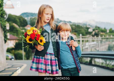 Ritratto all'aperto di un grazioso bambino con un bel bouquet di fiori autunnali. Moda scolastica per bambini, abbigliamento scolastico Foto Stock