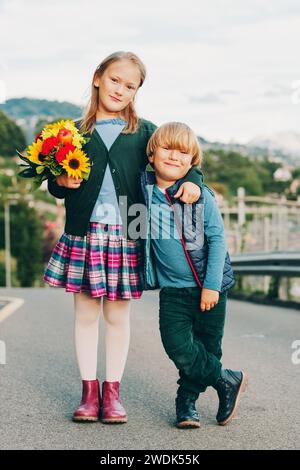 Ritratto all'aperto di un grazioso bambino con un bel bouquet di fiori autunnali. Moda scolastica per bambini, abbigliamento scolastico Foto Stock