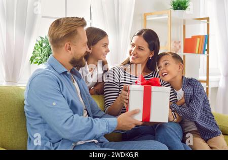 La donna felice riceve un bel regalo dal marito e dai bambini per la festa della mamma Foto Stock